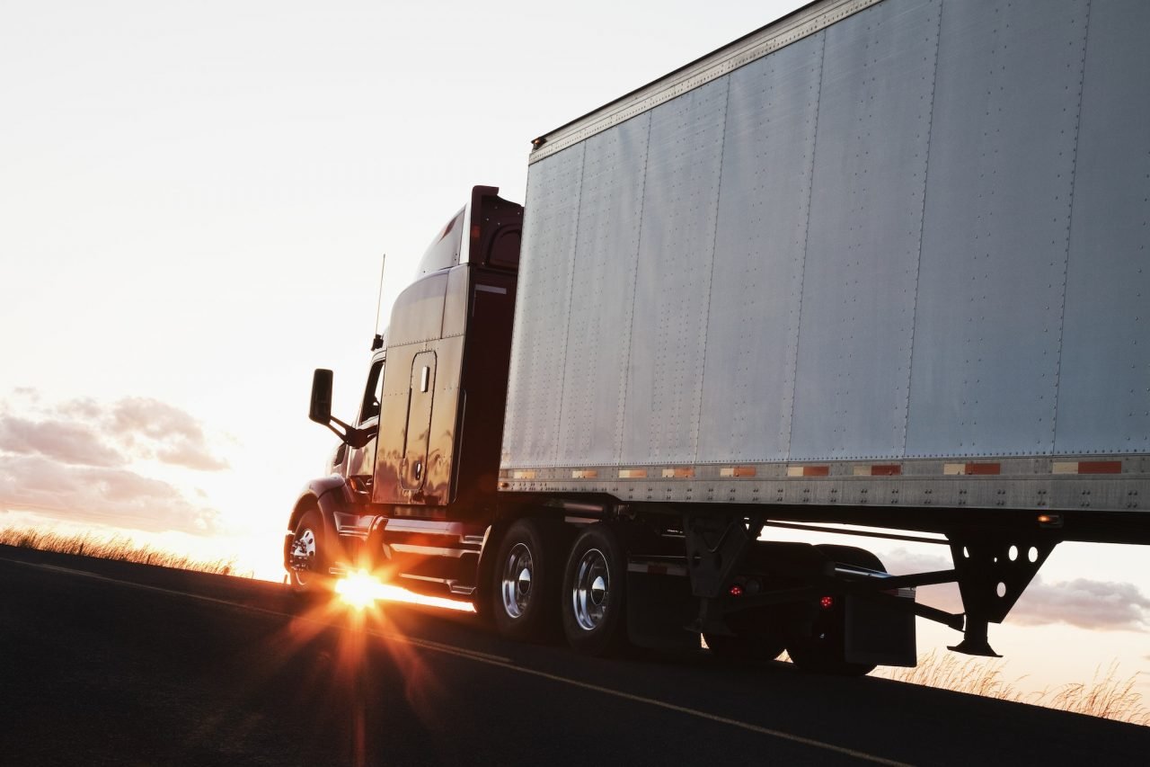 Rijdende Vrachtwagen op een snelweg bij zonsondergang